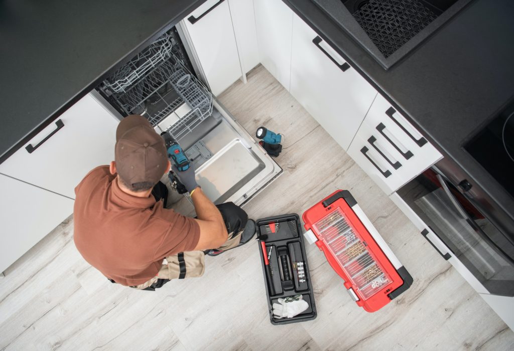 Technician Installing Dishwasher Inside Residential Apartment Kitchen